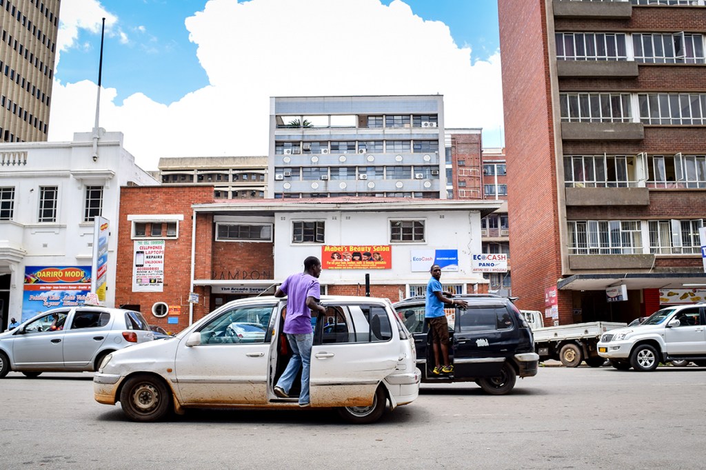 Pirate taxies illegally load people while stopped in the middle of the street in Harare, Zimbabwe.  (Linda Mujuru, GPJ Zimbabwe)