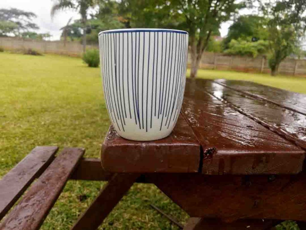 Coffee mug on a park bench in the rain