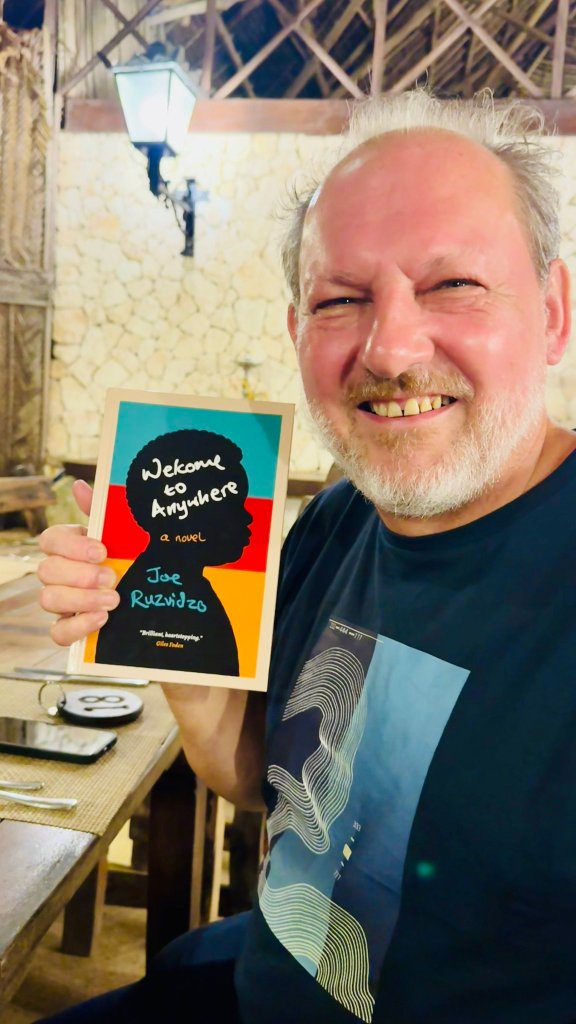 Giles Foden posing with signed copy of Welcome To Anywhere